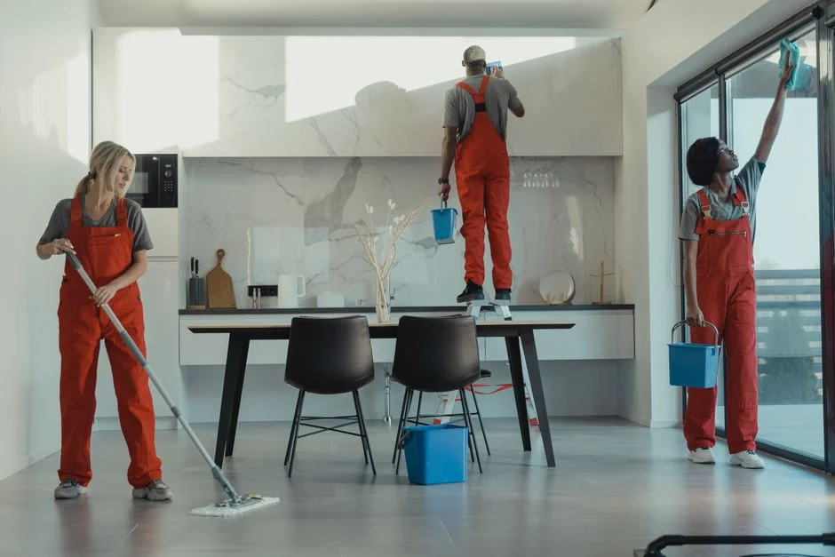 gallery-02 A professional cleaner in protective gear vacuuming the floor in a modern living room.